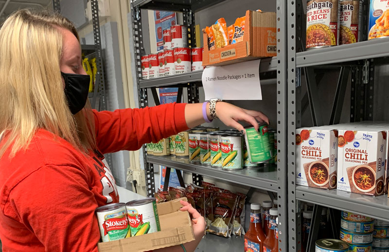 LCC Head Volleyball Coach, Haley Miller, stocks the student food pantry with canned goods.